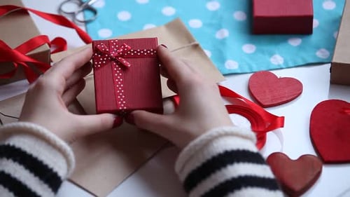 Hands Presenting a Small Red Gift Box