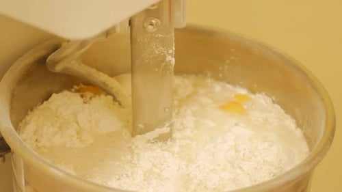 Der Bäcker fügt der professionellen Spiralknetmaschine Zutaten hinzu