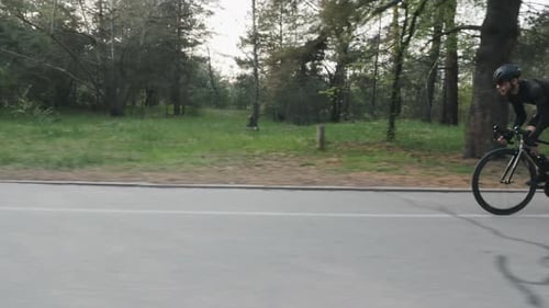 Man Cycling fast strong pedaling riding a bicycle in park at sunset out of the saddle