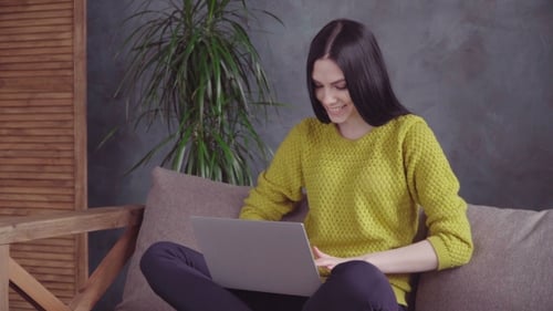 Woman Using Laptop Relaxing on Couch Indoors