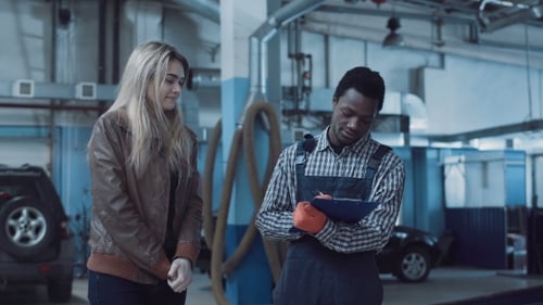 Woman Discussing Auto Repair with Mechanic in Garage