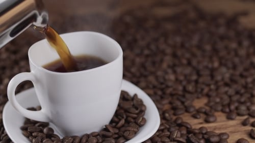 Pouring Dark Coffee into a White Mug