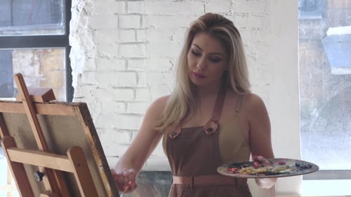 Woman Artist Working in Her Studio, Paints Oil on Canvas