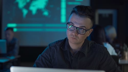 Person Typing at Laptop in a Dark Office
