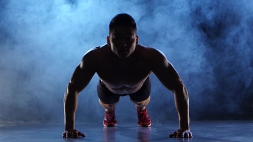 Push Ups Bodybuilder asiatique. Fond de fumée noire. La silhouette