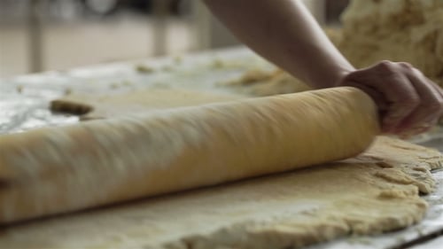 Flattening Dough with Rolling Pin in Workplace