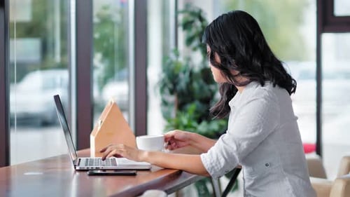 Woman Working at Laptop in Modern Cafe