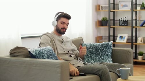 Man Relaxing On Couch With Headphones and Phone