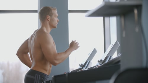 Muscular Man Running On A Treadmill In The Gym