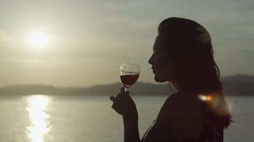 Slow Motion Video of a Girl Drinking Wine From a Glass at Sunset By the Sea