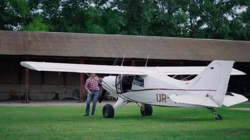 Adult near a small airplane on grass airfield