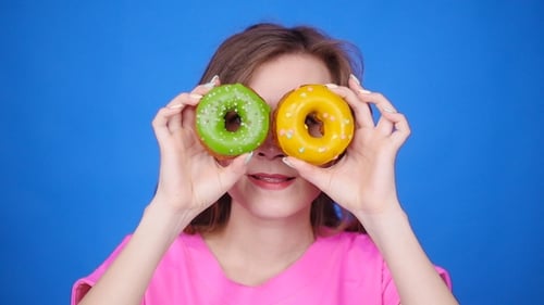 Woman Posing with Colorful Donuts on Blue Backdrop