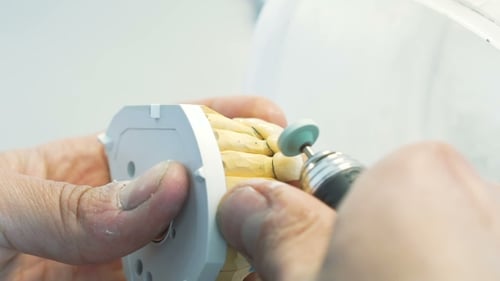 Dental Technician Shaping False Teeth with Rotary Tool