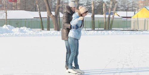 Couple Ice Skating on Outdoor Rink in Winter