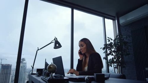 Woman Working at Desk Talking on Phone in Office
