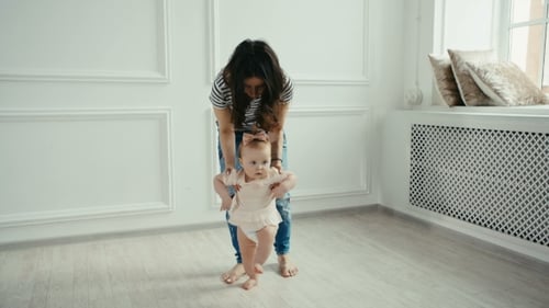 Cute Baby Taking First Steps with Mother