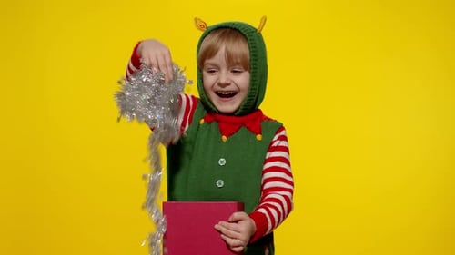 Cheerful Child Opens Christmas Gift, dressed as Elf