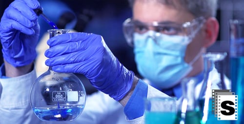 Scientist Adds Blue Liquid to Flask in Lab