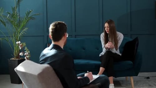 Young Woman Visiting Male Psychologist Sitting on the Comfortable Couch During Psychological Session