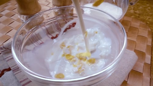 Cornflakes Cereal and Milk Being Poured in Bowl