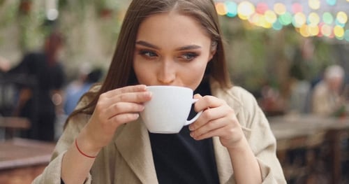 Young Woman Drinks Coffee at Cafe