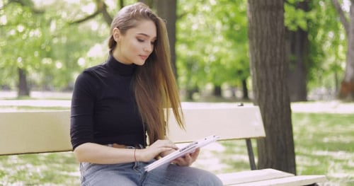 Young Woman Using Tablet on Park Bench