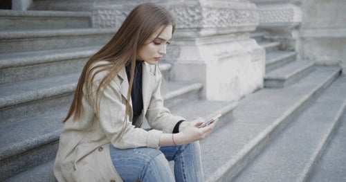 Stylish Woman Uses Smartphone Sitting on Urban Steps