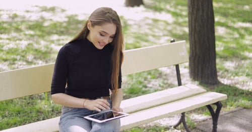 Woman Uses Tablet on Park Bench