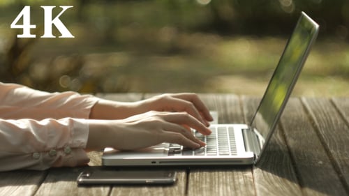 Woman Typing on Laptop in Rural Outdoor Setting