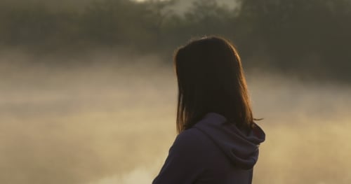 Woman Looks at Foggy Lake During Sunrise