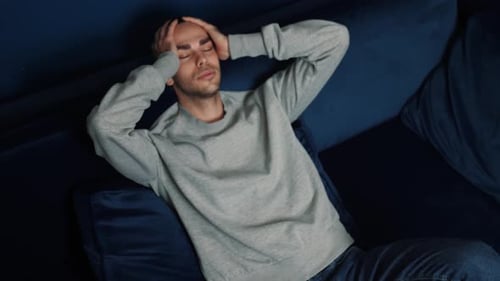 Man Lying on Sofa Thinking and Stretching