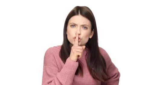 Porträt einer empörten Frau mit braunen Haaren, die den Zeigefinger auf die Lippen legt und streng aussieht, was bedeutet, dass sie