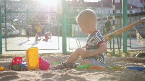 Child Plays with Toys in Sandbox Playground
