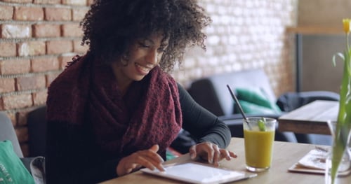 Smiling Woman Using Tablet in Urban Cafe