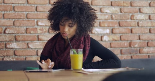 Woman Uses Tablet and Sits Near Brick Wall