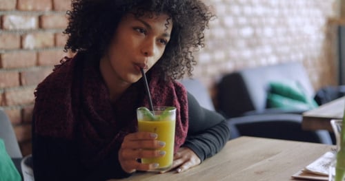 Woman Drinking Smoothie at Cafe Table