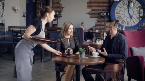 Waiter Delivering Order. Female Waiter Delivering Order for Young Couple Sitting in Cafe.