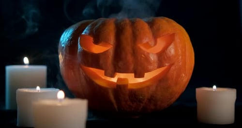 Glowing Jack O'Lantern Surrounded by Candles in Dark