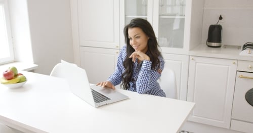 Smiling Woman Using Laptop in Kitchen