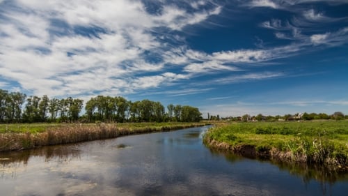 Fluss im Frühling an einem strahlend sonnigen Tag. Blauer Himmel mit weißen Wolken