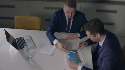 Businessmen Analyzing Charts and Graphs in Office Setting