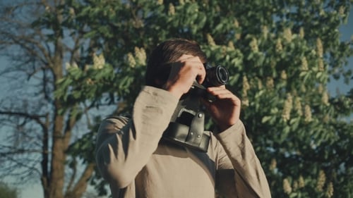 Man with Camera in Urban Park Taking Pictures