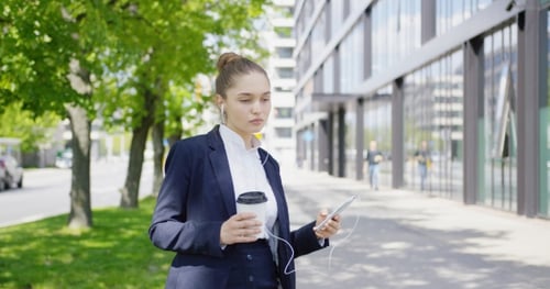 Businesswoman Walking with Coffee and Cell Phone