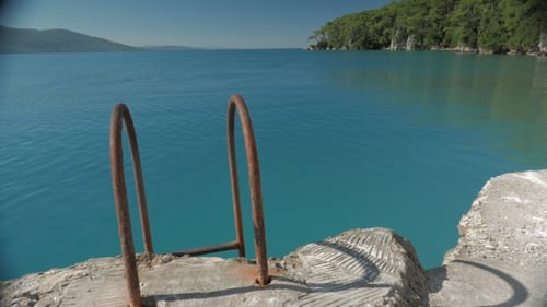 Bath Ladder with Rusted Handrails Leading Up From the Sea to Steep Pier