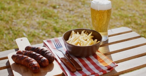 Grilled Sausages and Fries with a Beer Outdoors