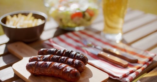 Grilled Sausages with Salad and Beer on Table