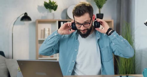 Guy in Headphones Enjoying Modern Music while Working on Computer in Home Office