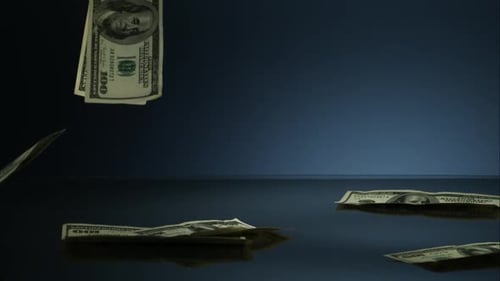 Amerikanische 100-Dollar-Scheine fallen auf eine reflektierende Oberfläche