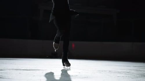 La patineuse artistique porte des vêtements de sport noirs patine sur la patinoire s'entraîne seule la nuit