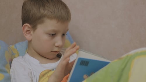Kid Reading Book at the Bed